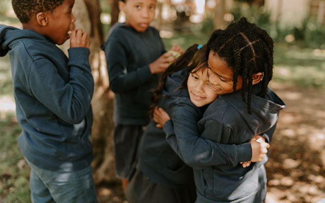 Children embracing at Three Peaks School