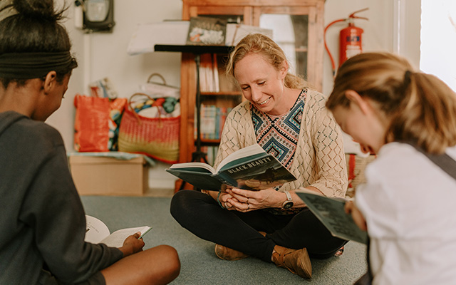 A teacher reading with children at Three Peaks School